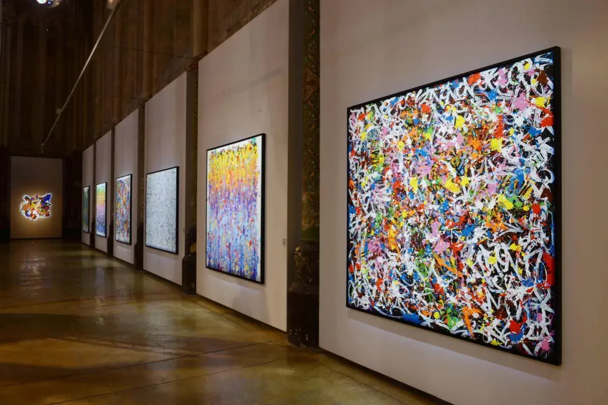 Une exposition d'art vibrante, avec des toiles colorées de **JonOne** côte à côte, capturant l'énergie du graffiti.