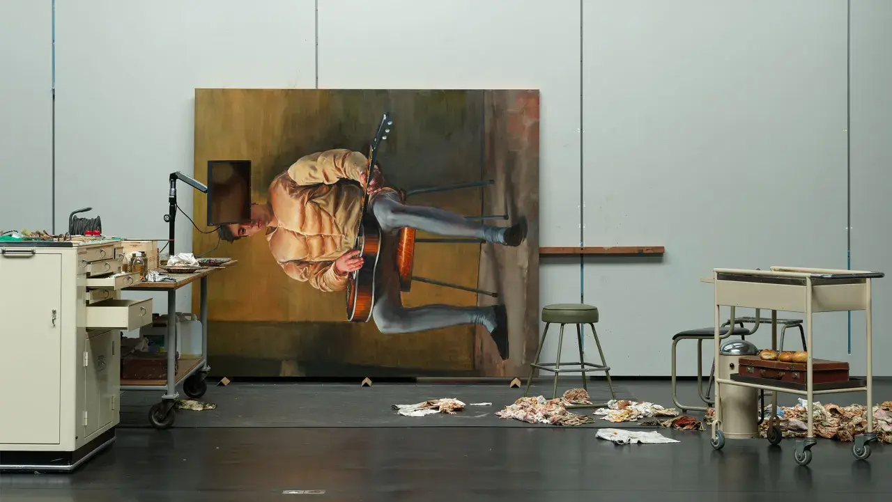 Dans l'atelier de Michael Borremans, un tableau monumental représente un homme jouant de la guitare, suspendu dans un espace onirique.