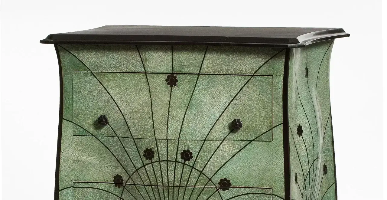 Meuble art nouveau vert texturé, orné de motifs floraux et de lignes courbes rappelant des éventails.