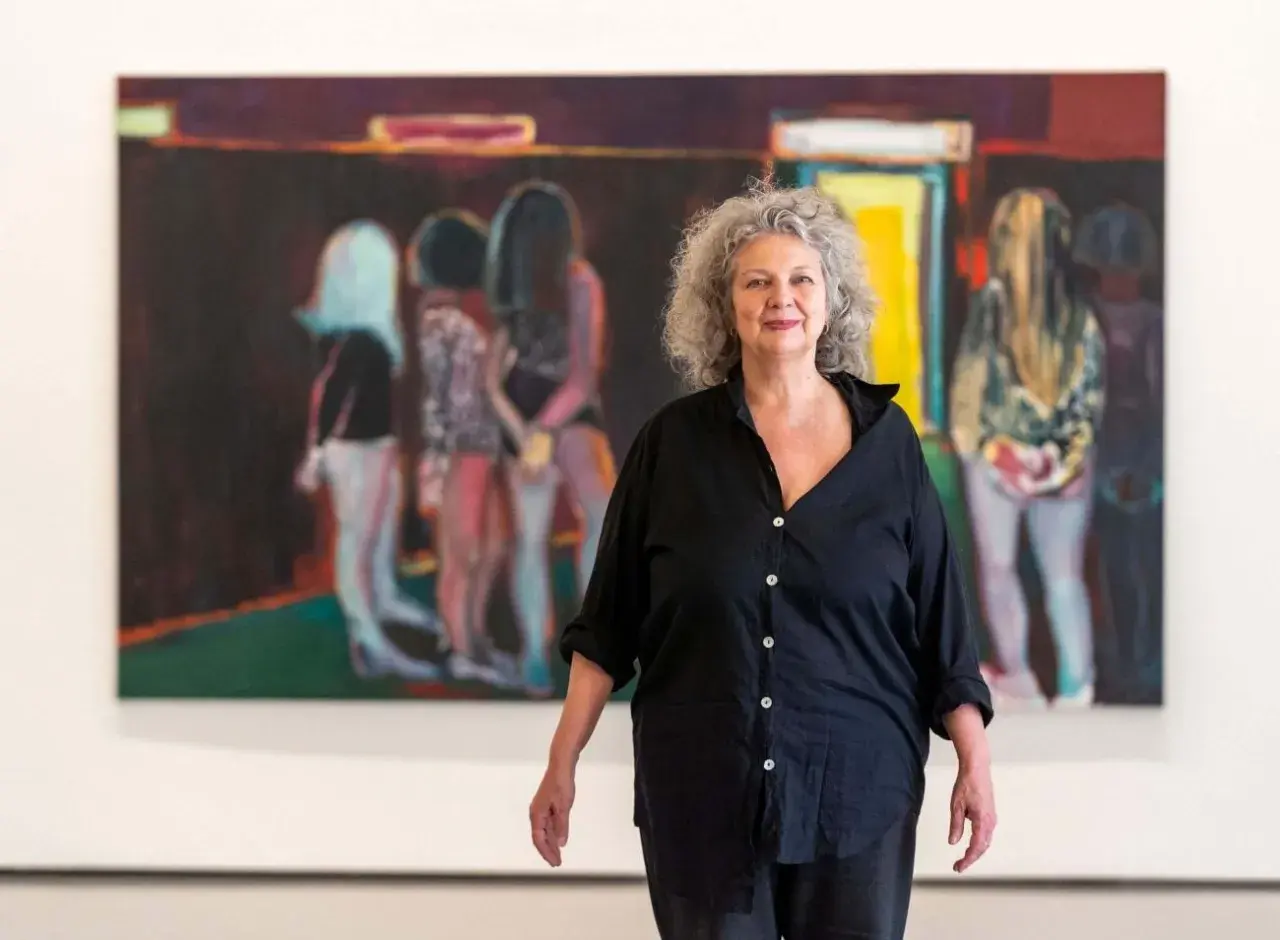 La peintre Marlene Dumas pose devant ses œuvres d'art, des figures floues dans des teintes vives.