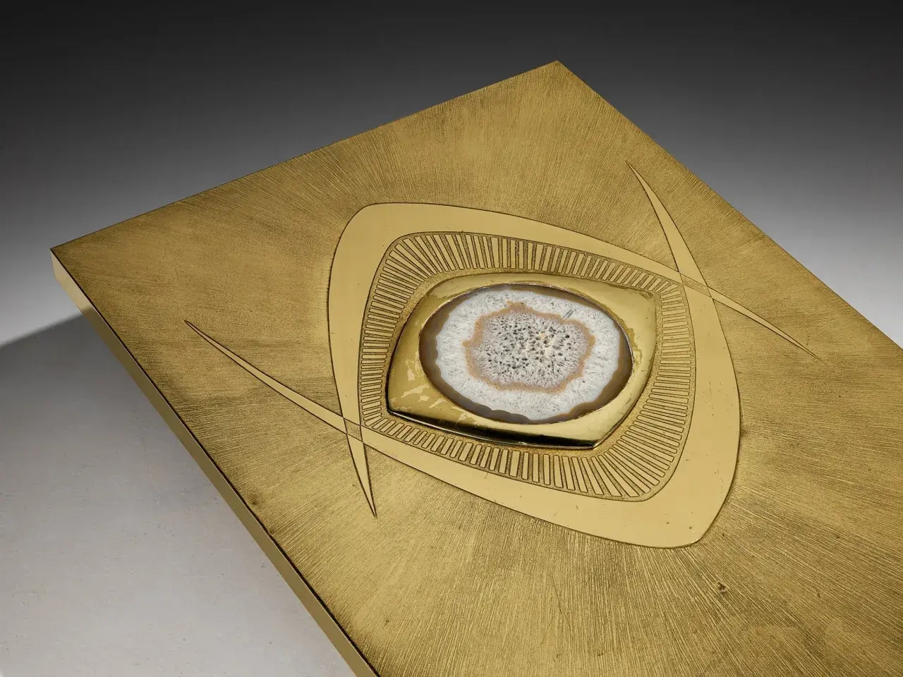 Plaque en laiton brossé avec une agate polie incrustée, ornée de motifs géométriques stylisés.