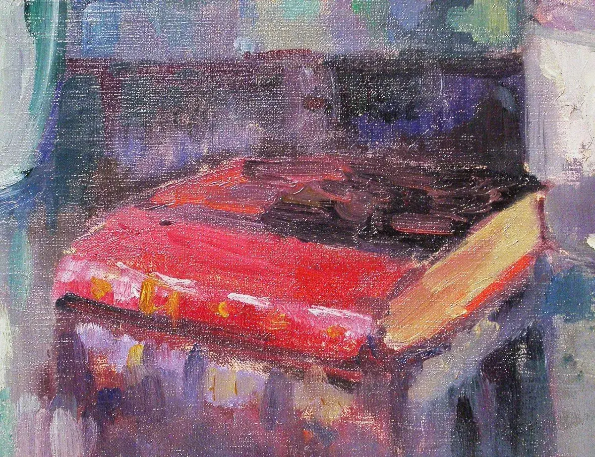 Un livre rouge vif, peut-être une œuvre de Robert Antoine Pinchon, repose sur une table, baigné de lumière.