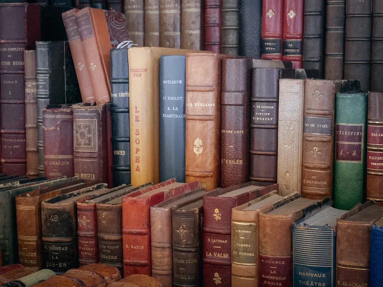 Une pile de livres anciens aux reliures variées. Obtenez une estimation livres anciens gratuit pour vos trésors littéraires.