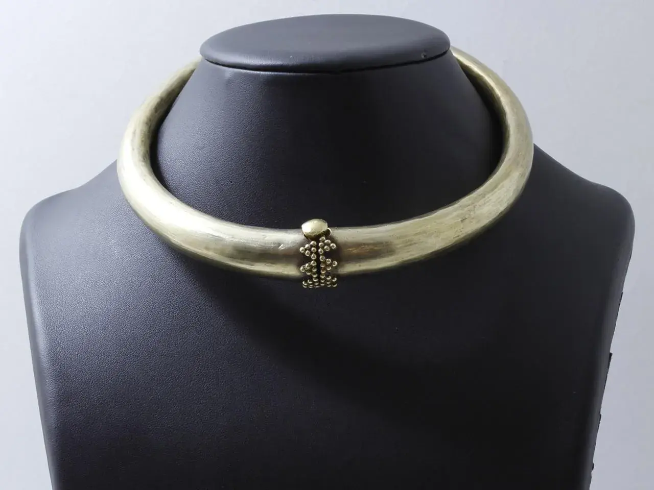 Collier rigide en laiton patiné, orné d'une grappe de perles. Un bijou d'exception, digne d'un prix Goudji.