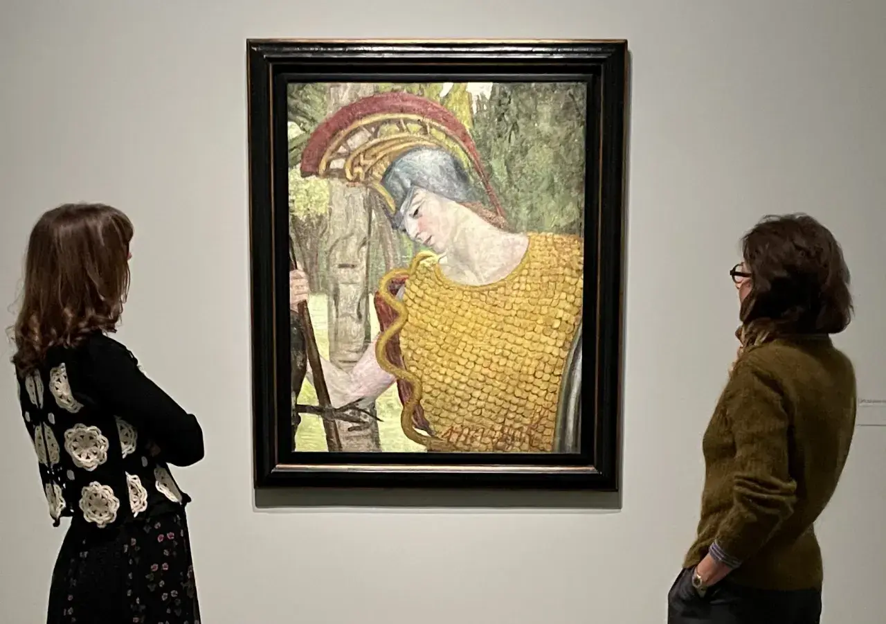 Deux femmes contemplent une peinture d'Hermine David représentant une figure casquée en armure dorée, tenant une lance.