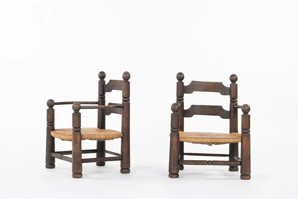 Deux fauteuils d'enfant en bois sombre, assises en paille tressée, style Charles Dudouyt.