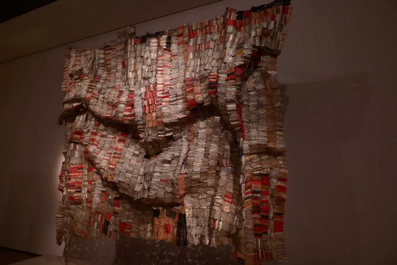 Œuvre monumentale d'El Anatsui, un rideau de bouchons de bouteilles en aluminium et cuivre, aux reflets changeants, évoquant des tissus précieux.