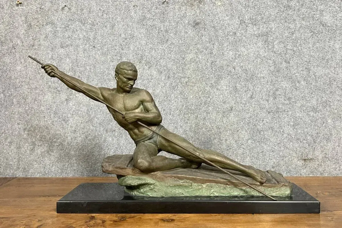 Sculpture en bronze ou régule d'un athlète lançant un javelot, posé sur un rocher.