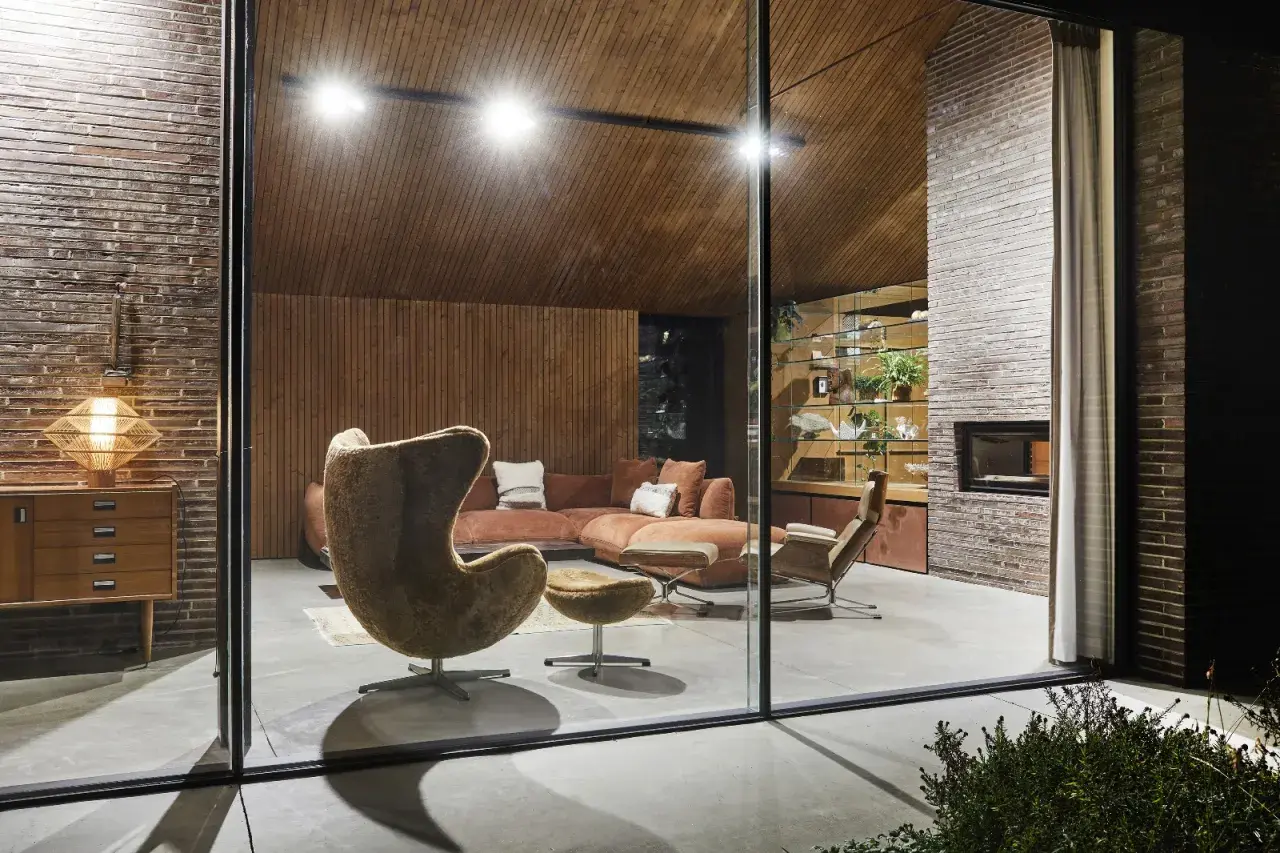 Salon au design mid century modern avec fauteuil œuf, canapé modulable et cheminée en brique.