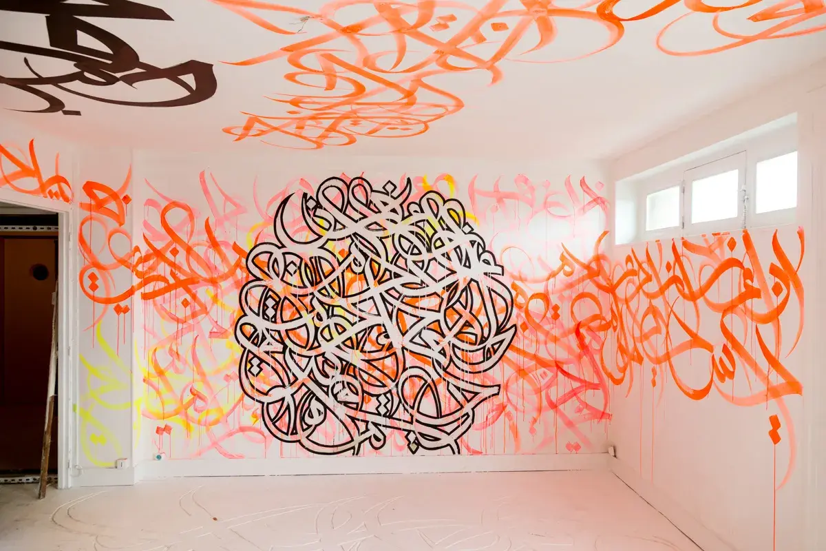Un mur et un plafond recouverts de calligraphie arabe vibrante, comme si el seed avait semé des mots dans cet espace.