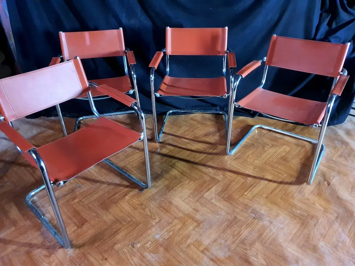 Quatre chaises modernes en cuir orange, style Matteo Grassi, sur un parquet en bois.