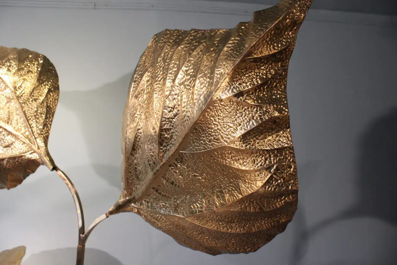Sculpture de feuilles dor&eacute;es textur&eacute;es, style Tommaso Barbi, sur fond gris.