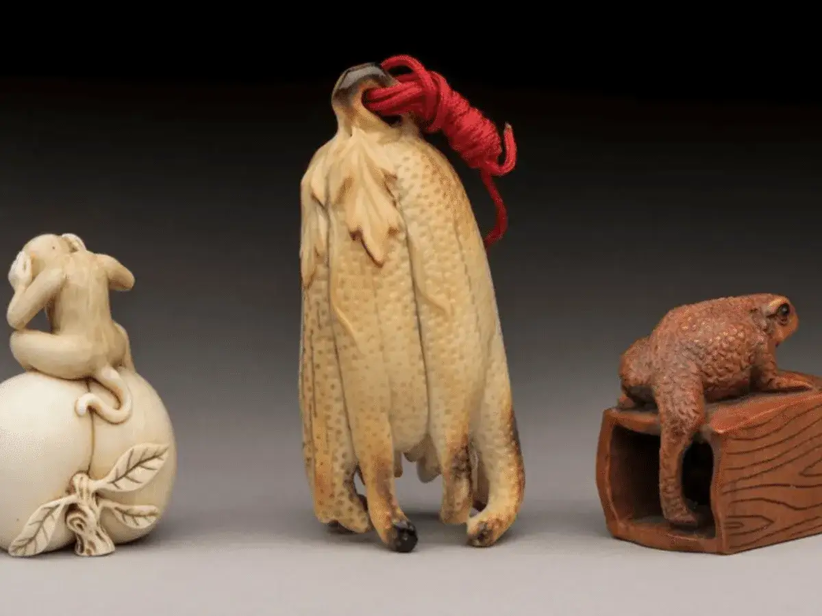 Trois objets d'art : un singe en ivoire sur une p&ecirc;che, une grappe de fruits stylis&eacute;e, et un crapaud sur un socle. Id&eacute;es pour que faire de ses objets en ivoire.