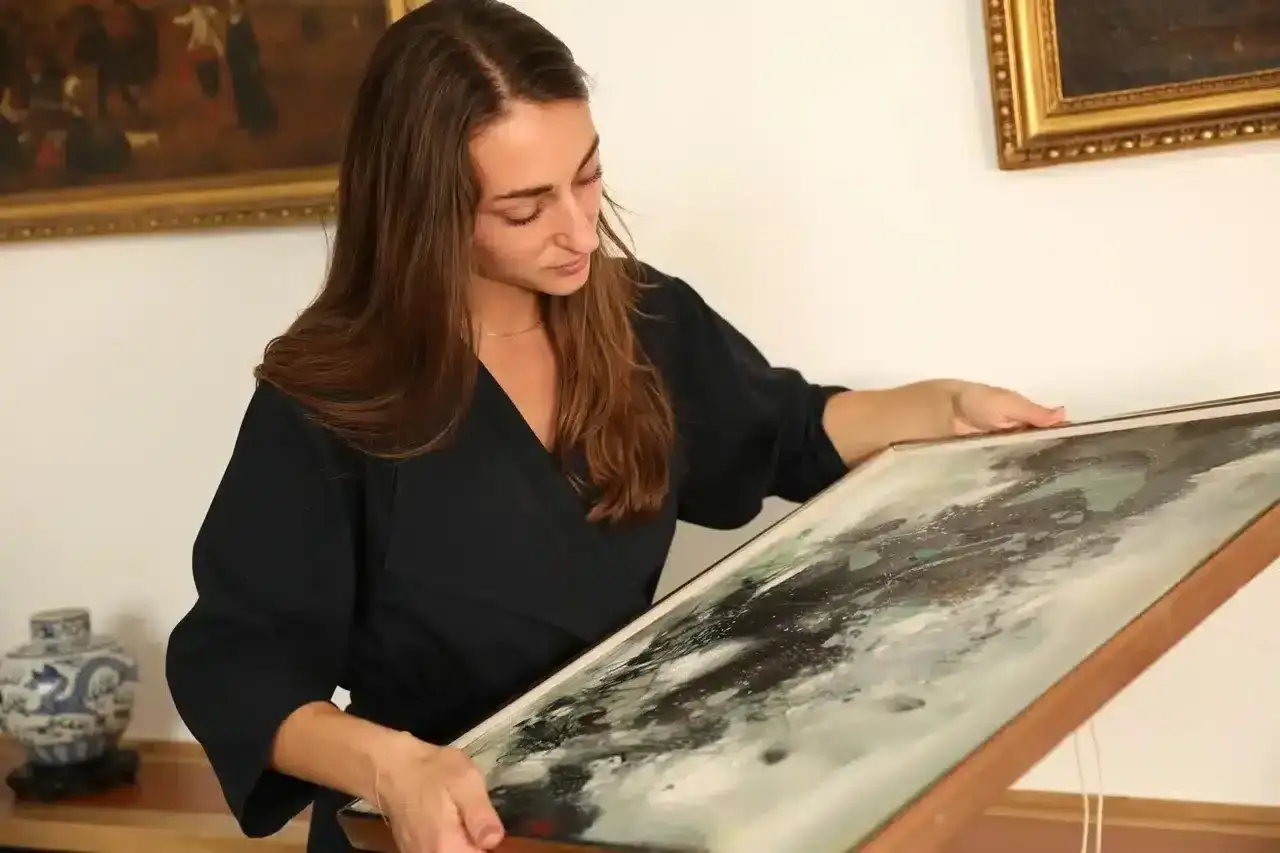 Une femme examine un tableau abstrait, prête à le faire estimer gratuitement.