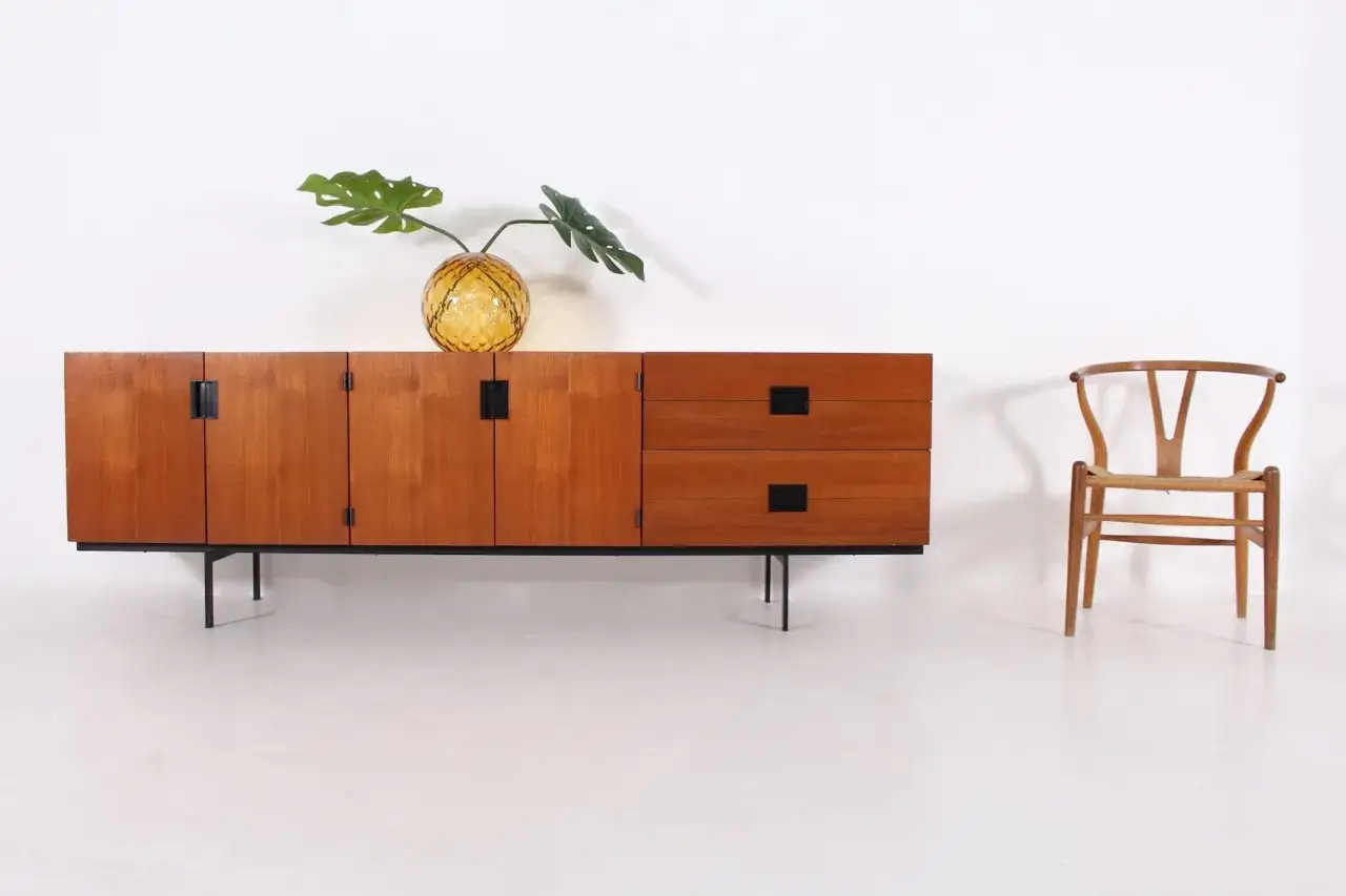 Buffet en teck Cees Braakman, avec un vase en verre jaune et une chaise Wishbone &agrave; droite.
