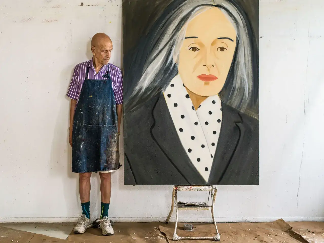 Alex Katz, artiste peintre, pose devant son portrait d'une femme aux cheveux argent&eacute;s, dans son atelier.