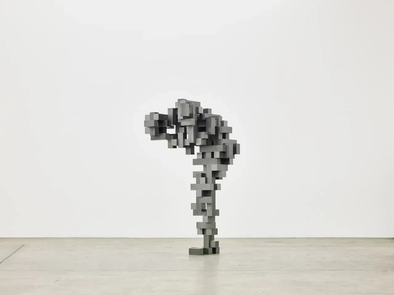 Sculpture abstraite en blocs de métal, évoquant une silhouette penchée, dans le style d'Antony Gormley.