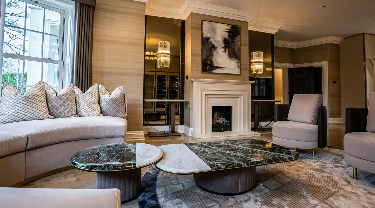 Salon luxueux avec canap&eacute; incurv&eacute;, tables basses en marbre, chemin&eacute;e et fauteuils. L'ambiance est chic et moderne, un style que Luciano Frigerio aurait appr&eacute;ci&eacute;.