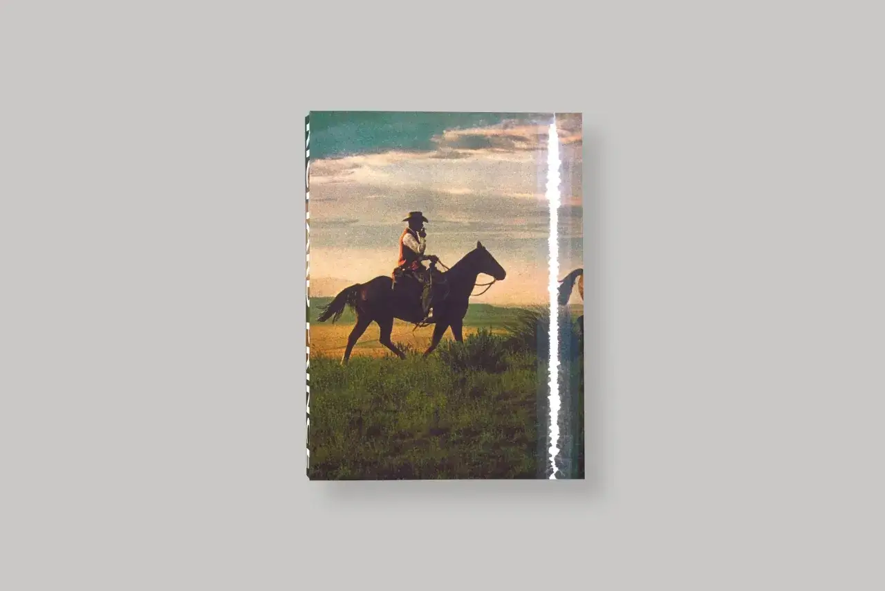 Un cow-boy sur son cheval, une œuvre de Richard Prince, traverse un champ verdoyant sous un ciel nuageux.