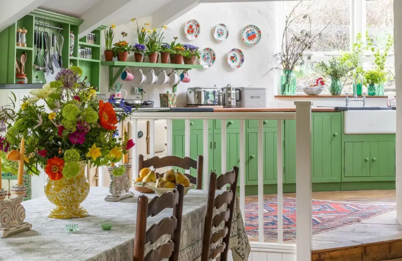 Ambiance chaleureuse d'une cuisine d&eacute;coration style cottage ou campagne chic, avec un bouquet color&eacute;, des &eacute;tag&egrave;res vertes et des assiettes d&eacute;coratives.