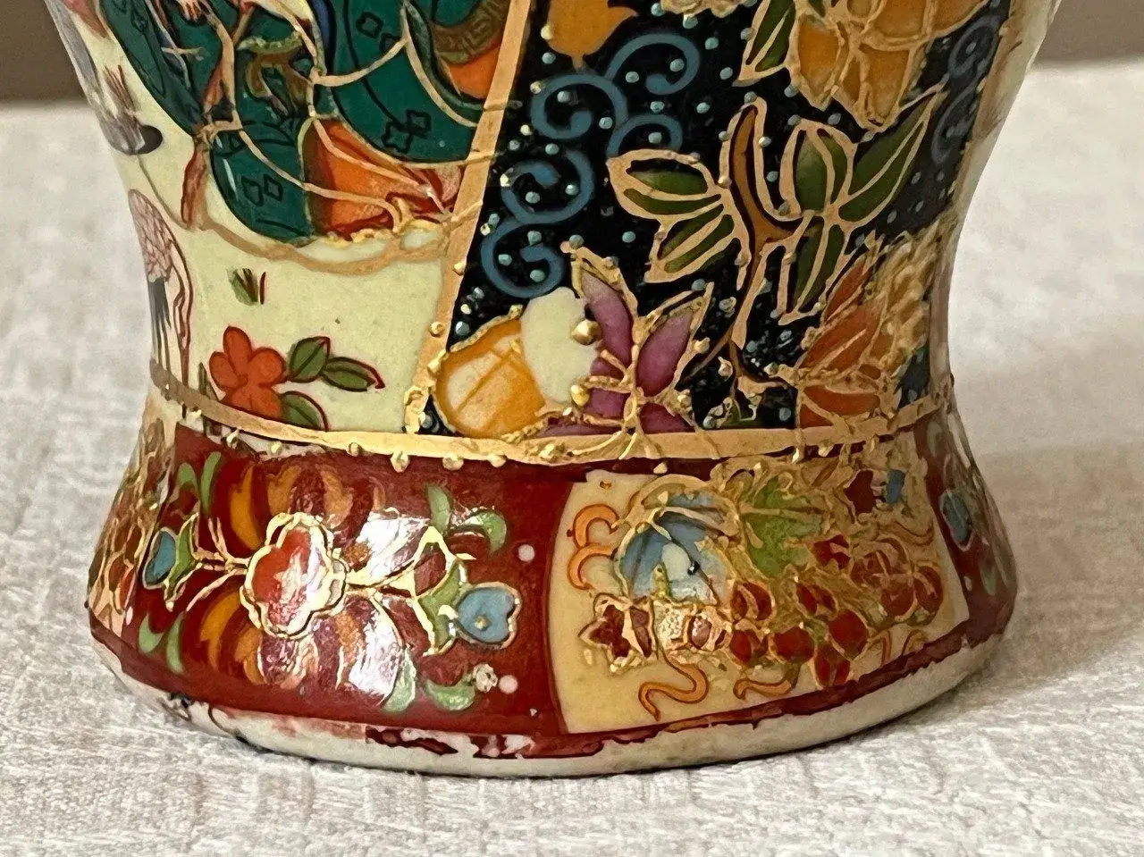 D&eacute;tail d'un vase chinois ancien orn&eacute; de motifs floraux et de personnages, avec une signature discr&egrave;te.