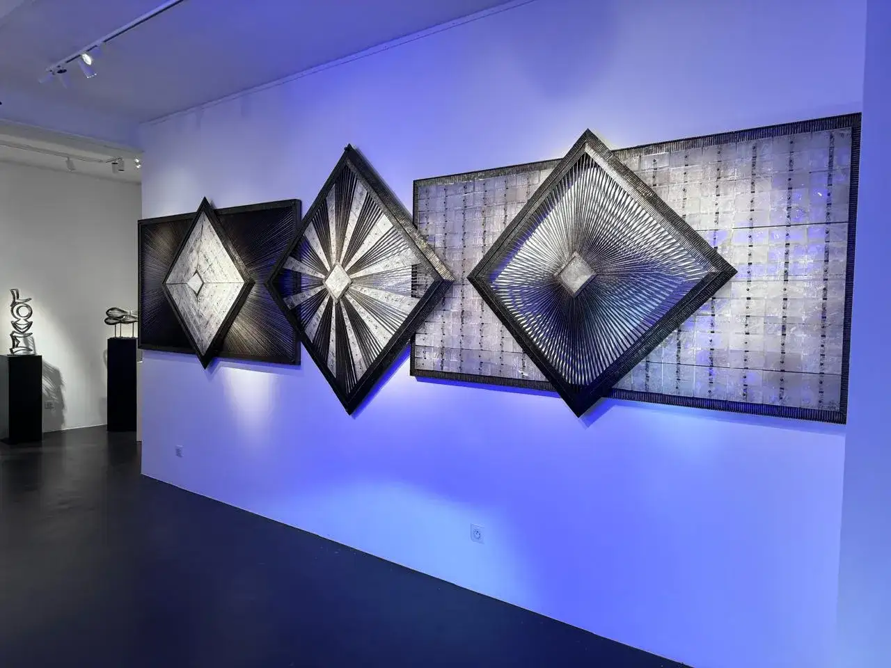 &OElig;uvres de Sylvain Subervie dans une galerie, avec des formes g&eacute;om&eacute;triques lumineuses sur fond bleu.